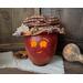 A candle lights the smile of a fall apple gourd decoration. The gourd has a happy face carved into it. This gourd collectable is named Mac.